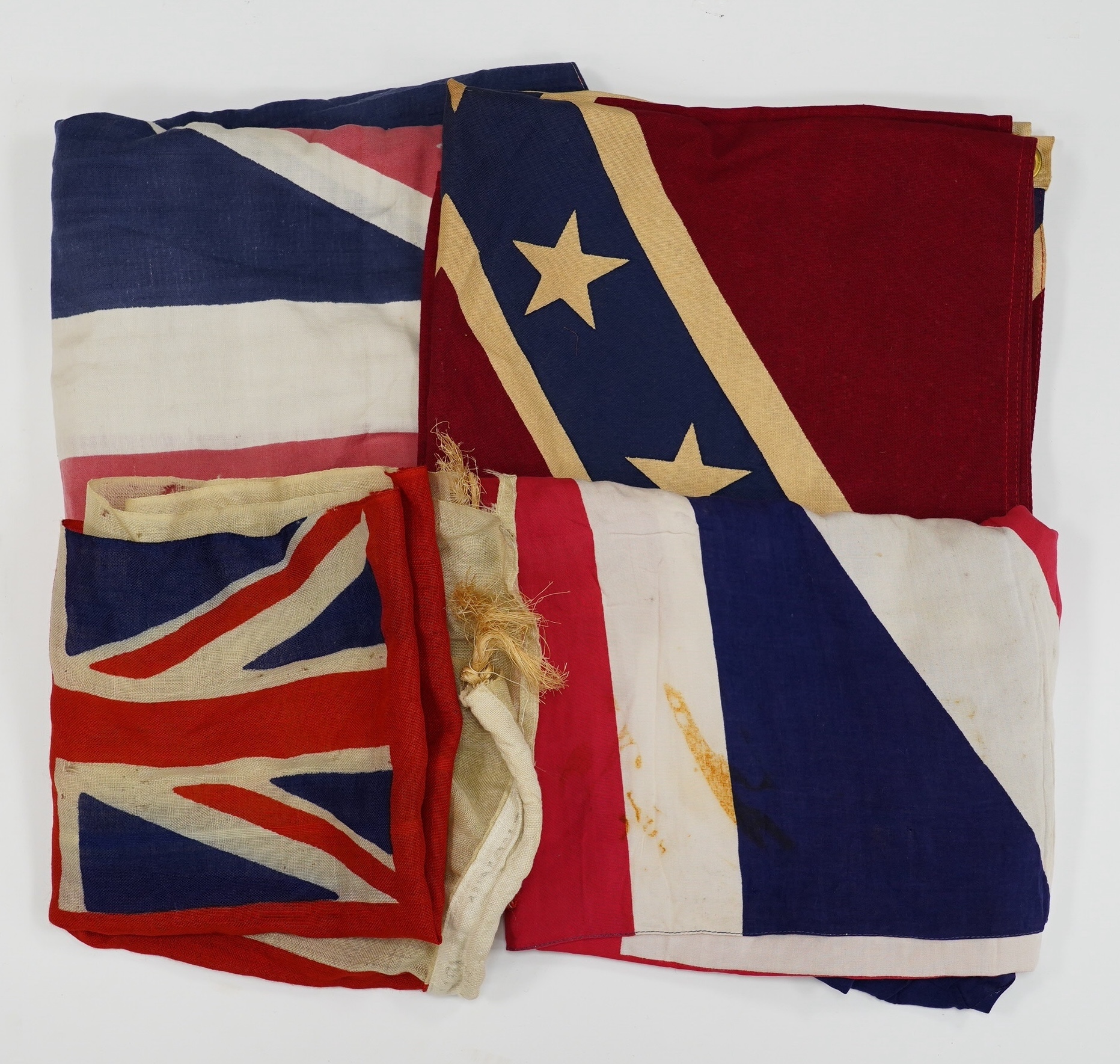 Four early to mid 20th century flags including; two Union Jack flags, a British naval ensign and an American confederate flag, 62 x 86cm. Condition - poor to fair